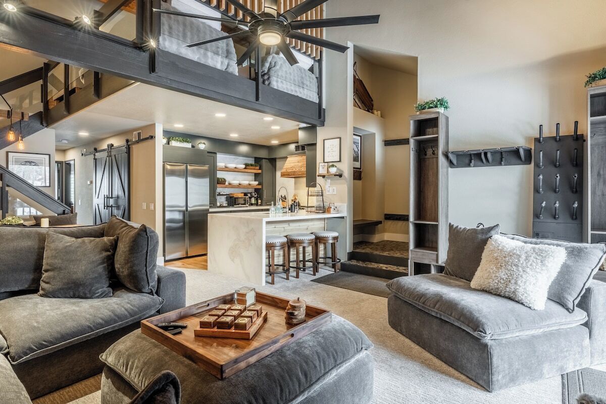 A modern living room with a high ceiling, a central island, and a kitchenette.