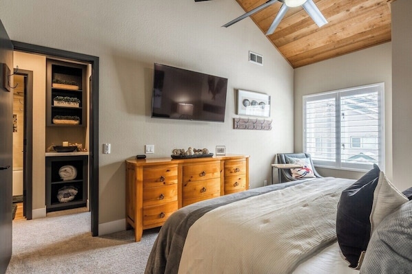 Un dormitorio con una cama, un aparador de madera, un televisor y una ventana con persianas.