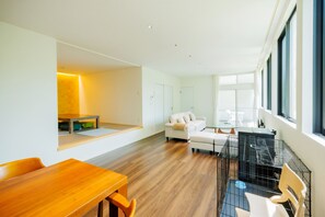 A modern living room with a wooden dining table, a white sofa, and a black pet cage.