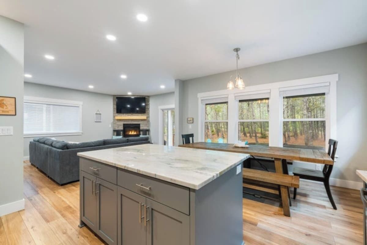 A spacious kitchen with a large island, a dining area with a wooden table, and a built-in fireplace.