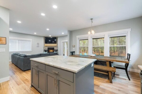 A spacious kitchen with a large island, a dining area with a wooden table, and a built-in fireplace.