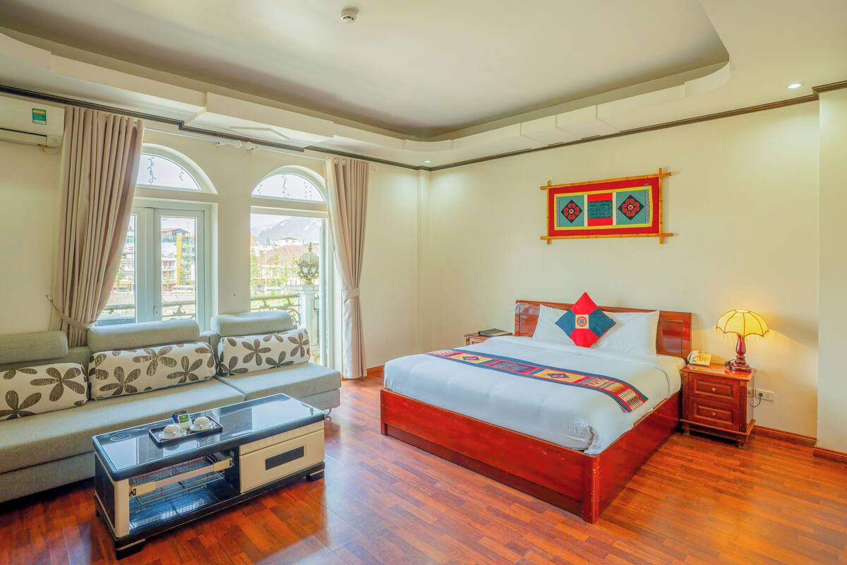 Une chambre d’hôtel avec un grand lit, un canapé, une petite table et une lampe.