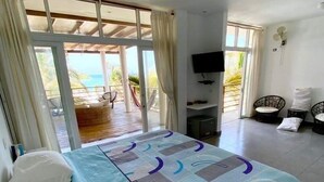 Ein Schlafzimmer mit Bett, Fernseher und Blick auf den Strand.