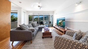 A modern living room with a grey sofa, patterned armchair, and a wooden coffee table.