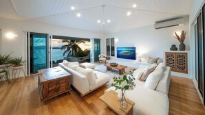 Un salón amplio con un sofá blanco, una mesa de centro de madera y un televisor.