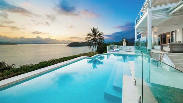 Una piscina infinita moderna con vistas claras al mar y una isla distante.