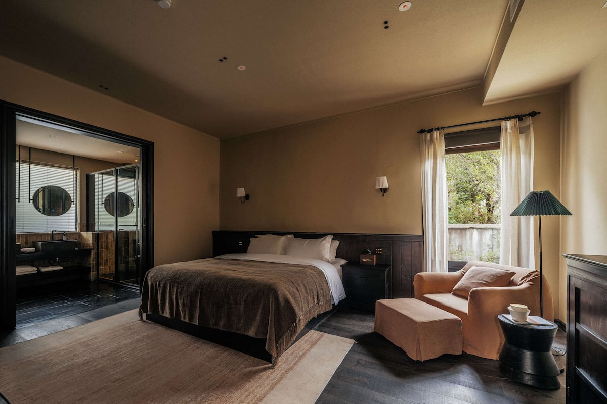 A modern bedroom with a large bed, a sofa, a small table, and a mirror.