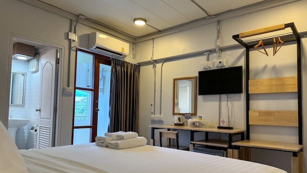 Una habitación de hotel con cama, escritorio con espejo, televisión y ventana con cortinas.