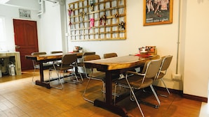 Un comedor con mesa de madera y sillas de metal, una pared decorada con un cartel y una repisa con botellas.
