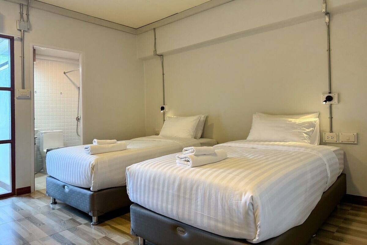 A hotel room with two beds, a shower, and a window.