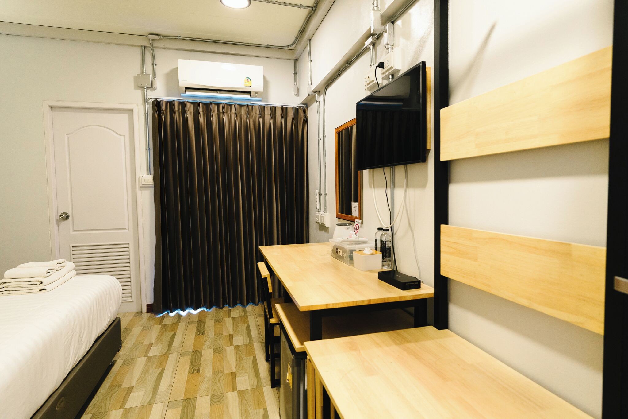 Een hotelkamer met een bed, een bureau, een stoel, een spiegel en een raam met gordijnen.