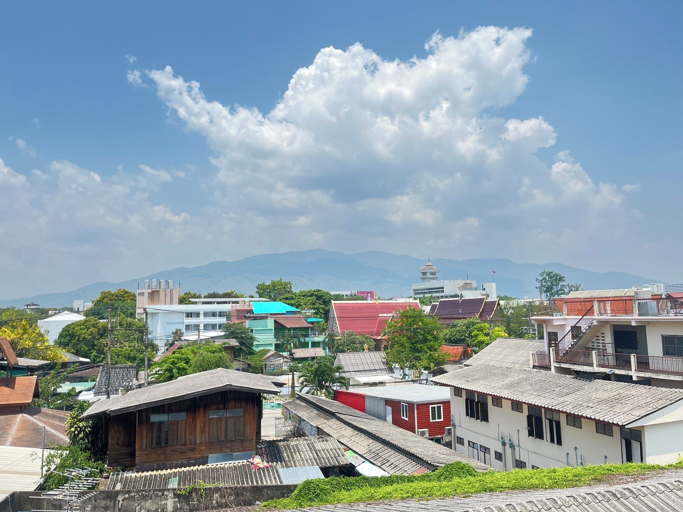 A view of a town with various buildings, including a pagoda, under a partly cloudy sky.
