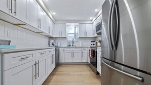 Una cucina moderna con mobili bianchi, elettrodomestici in acciaio inossidabile e pavimento in legno.