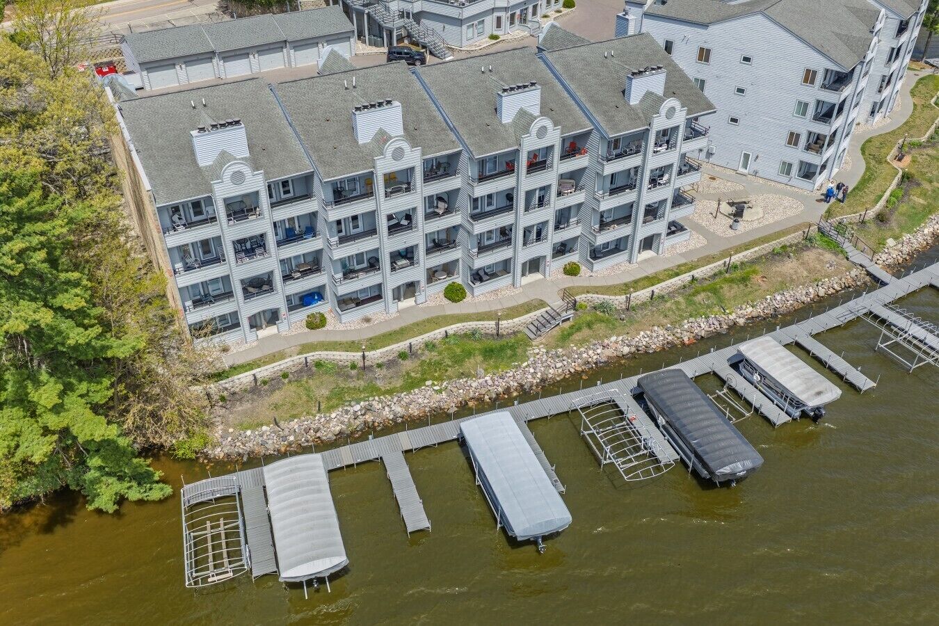 A multi-story hotel with balconies, a dock with boats, and a river.