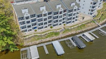 A multi-story hotel with balconies, a dock with boats, and a river.