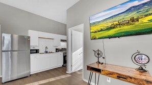 Eine moderne Küche mit weißen Schränken, einem Edelstahl-Kühlschrank und einem Holzespeisetisch mit einer Uhr.