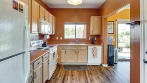 A compact kitchen with wooden cabinets, a built-in oven, and a window providing natural light. - Hot Tub Access & Fire Pit: Green Valley Getaway! (Green Valley)