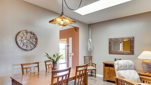 A dining area with a wooden table and chairs, a decorative clock, a hanging light fixture, and a mirror on the wall. - Hot Tub Access & Fire Pit: Green Valley Getaway! (Green Valley)