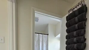 Ein Badezimmer mit Toilette, Duschvorhang und Handtuchhalter mit Handtüchern.