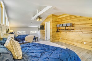 A bedroom with two beds, wooden walls, a TV, and a small shelf with baskets. - Cumberland Lake Retreat: Furnished Deck & Grill! (Burnside)