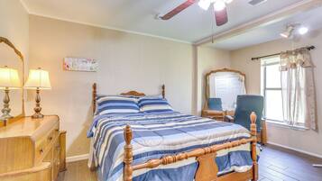 Ein Schlafzimmer mit einem Holzbett, einem Schminktisch, einem Spiegel und einem Deckenventilator.
