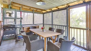 Une terrasse extérieure couverte, équipée d’une table et de chaises, d’un barbecue et d’un ventilateur.