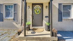 A house with a front porch, a door with a wreath, and two potted plants. - Walk to Detroit Zoo: Home w/ Sunroom & Patio! (Royal Oak)