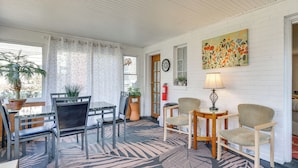A cozy room with a dining table, chairs, a sofa, and a coffee table. There is a potted plant, a clock, and a painting on the wall. - Walk to Detroit Zoo: Home w/ Sunroom & Patio! (Royal Oak)