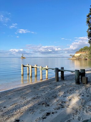A wooden pier extending into calm waters with a clear sky and distant land. - Peaceful & restorative Awhitu Peninsula retreat-80 minutes from Auckland CBD (Awhitu)