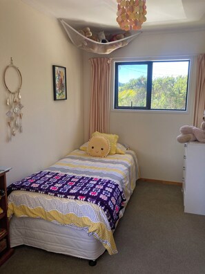 Une chambre à coucher avec un lit, une fenêtre, un bureau et un élément décoratif suspendu.