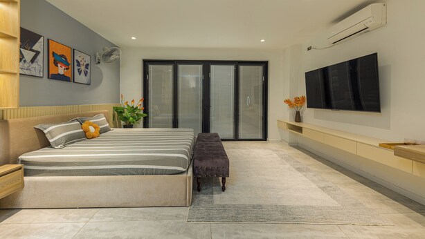 A modern bedroom with a large bed, a bench, a flat-screen TV, and a sliding glass door. - Thao Nguyen Homestay Ha Noi (Hanoi)