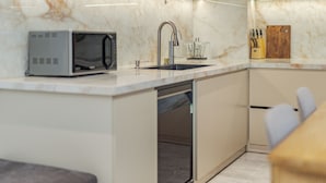 A modern kitchen with a built-in microwave, stainless steel sink, and a knife block. - Thao Nguyen Homestay Ha Noi (Hanoi)