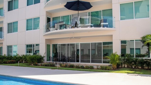 Een modern hotel met een zwembad, terras en een overdekt balkon.