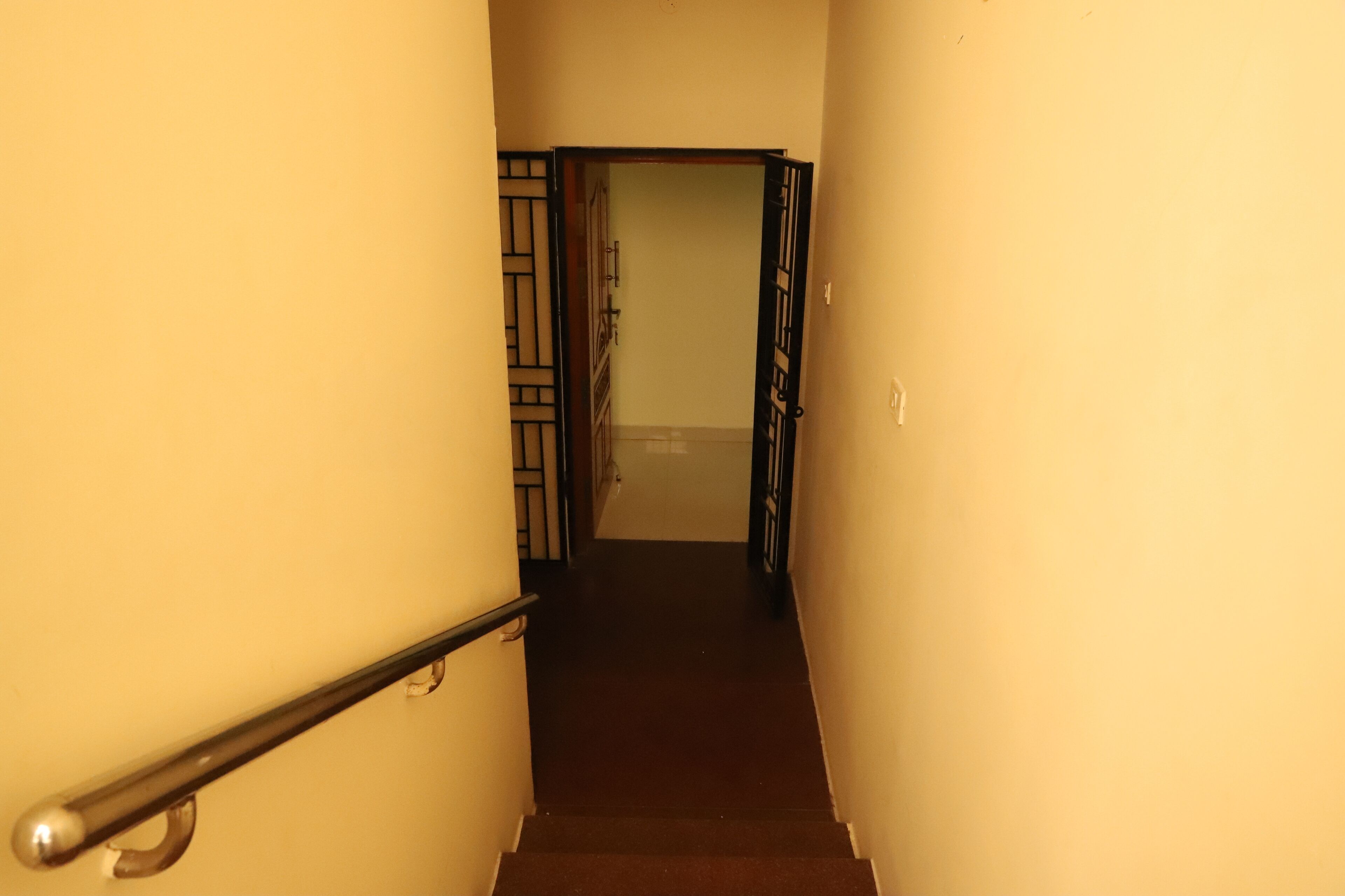 A narrow stairway with a handrail, leading to a door at the top.