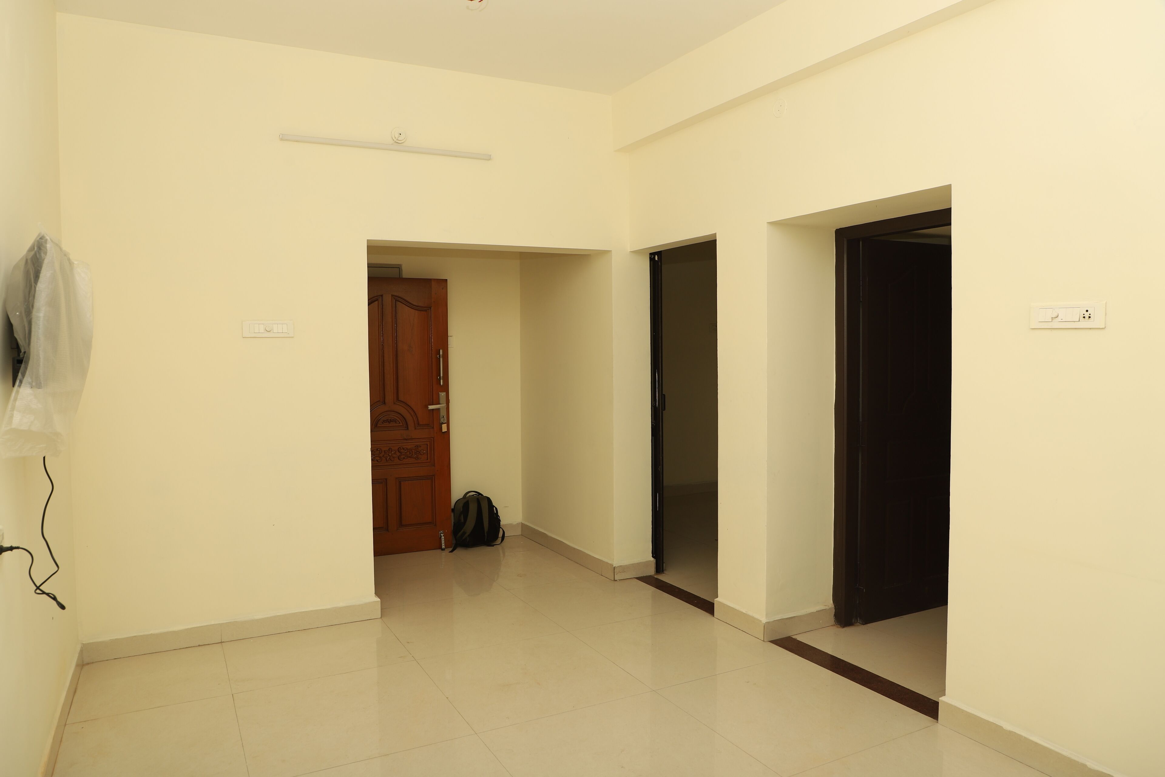 A hallway with a wooden door, a black door, and a bag on the floor.