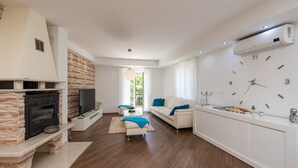 A modern living room with a stone fireplace, a flat-screen TV, a sofa, and a large wall clock. - Villa Kate - Dubrovnik by Villas Guide (Dubrovnik)