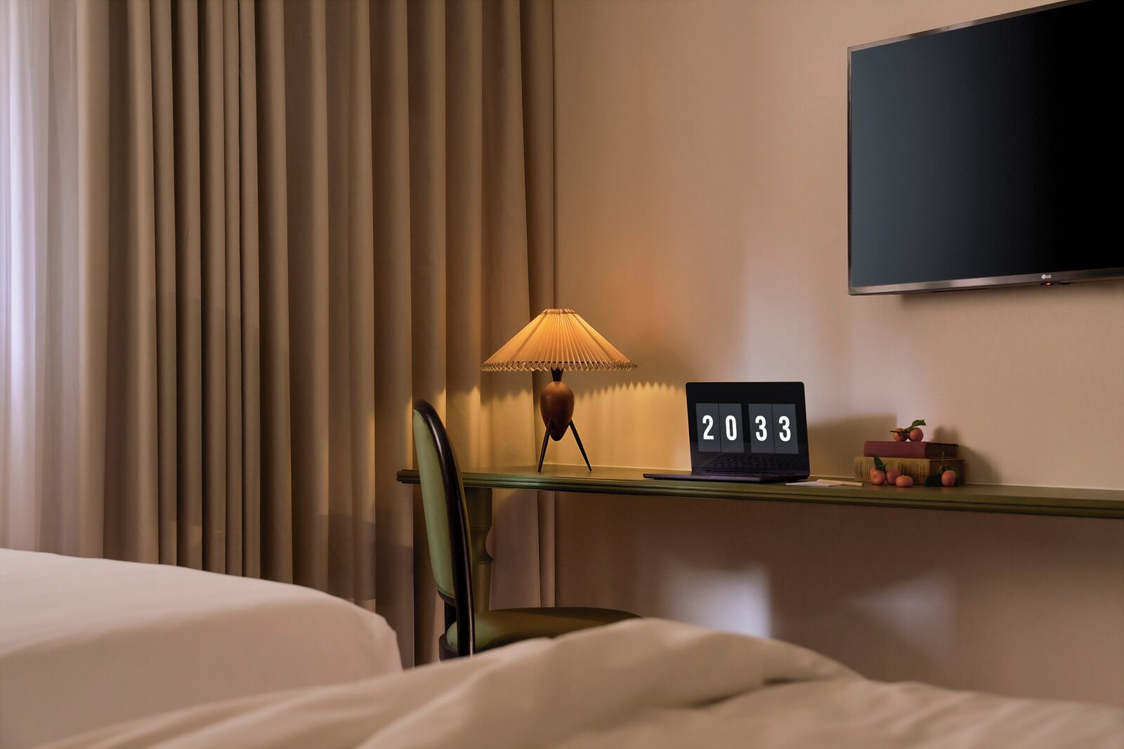 A hotel room with a bed, a desk with a lamp, a laptop displaying the year 2033, and a TV mounted on the wall.