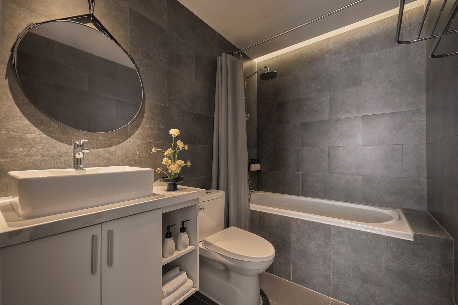 Een moderne badkamer met een grote spiegel, een wastafel, een toilet en een bad.