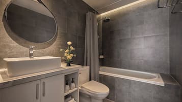 Een moderne badkamer met een grote spiegel, een wastafel, een toilet en een bad.