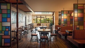 Un restaurante con muebles de madera, una mesa central y vistas a la vegetación exterior.