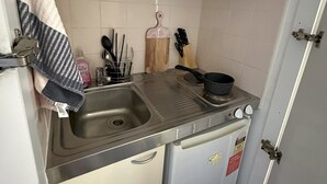 A compact kitchen with a microwave, sink, and a small refrigerator.