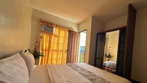 Un dormitorio con una cama, cortinas, una ventana y una puerta que da a un balcón.