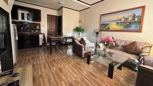 Una sala de estar moderna con una mesa de centro de vidrio, un sofá y un comedor con una cocina al fondo.
