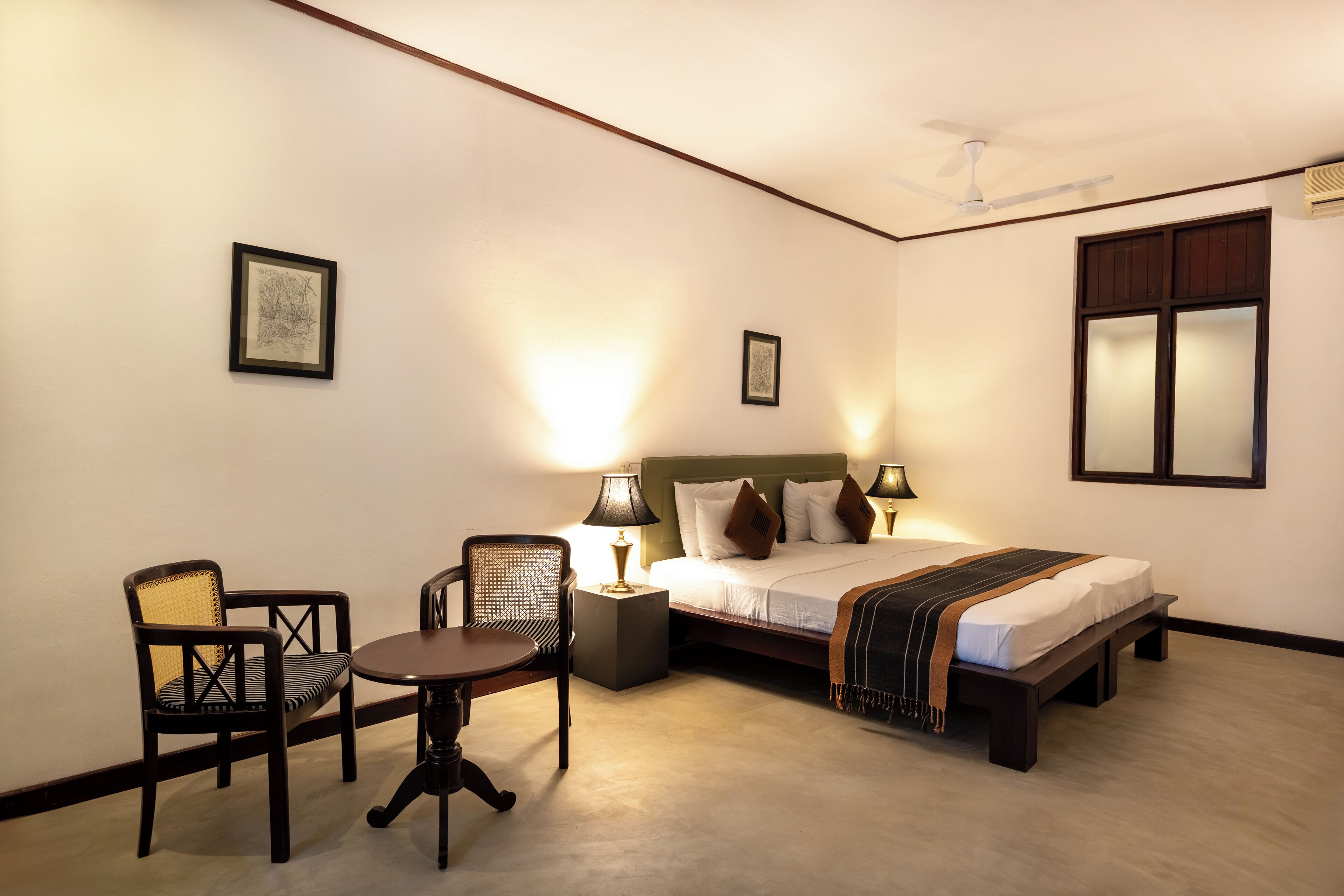 Una habitación de hotel con una cama, una silla, una mesita y dos lámparas de noche.