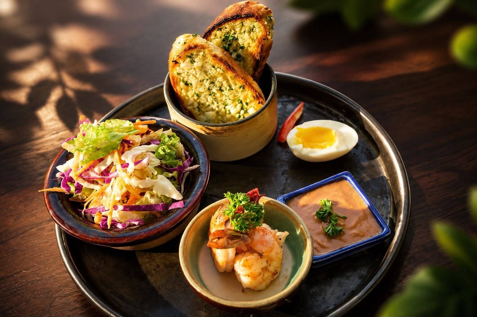 A meal consisting of a salad, shrimp, a boiled egg, and bread on a tray.