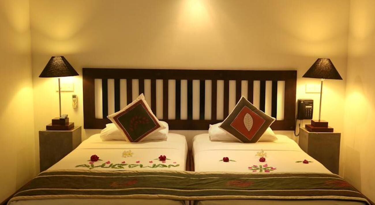 Ein Doppelzimmer mit zwei Betten, jeweils mit Kissen und Nachttischlampe.