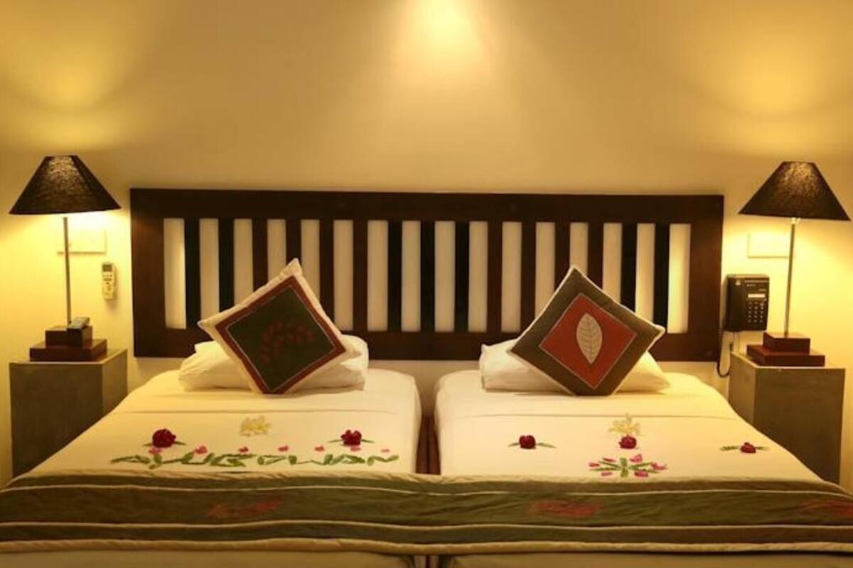 A double room with two beds, each with a pillow and a bedside lamp.