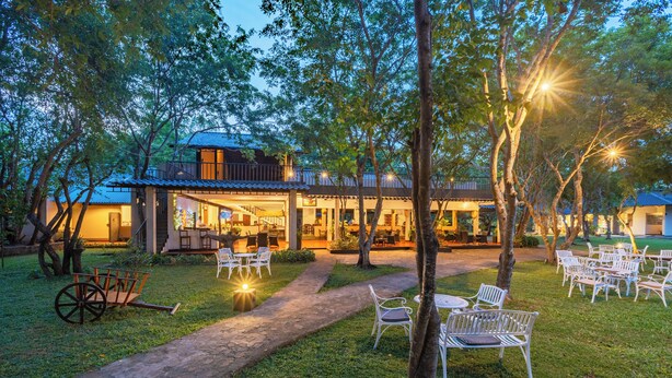 A courtyard with outdoor seating, a pathway, and a building with multiple levels and balconies. - Kassapa Lion Rock  (Sigiriya)