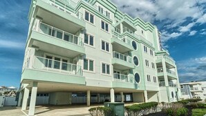 A multi-story building with balconies, a flat roof, and a parking area.