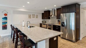 A modern kitchen with a central island, stainless steel appliances, and dark cabinetry.